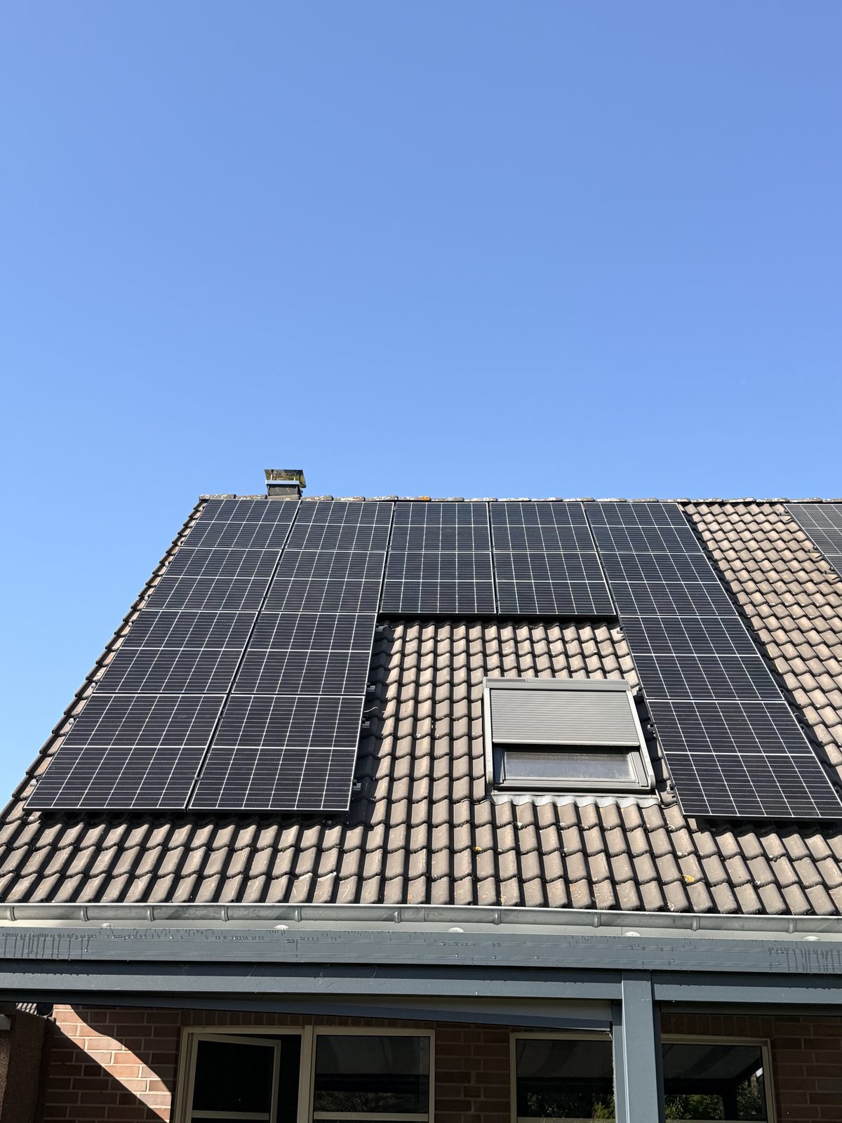 Ziegeldach mit Photovoltaikmodulen und Dachfenster