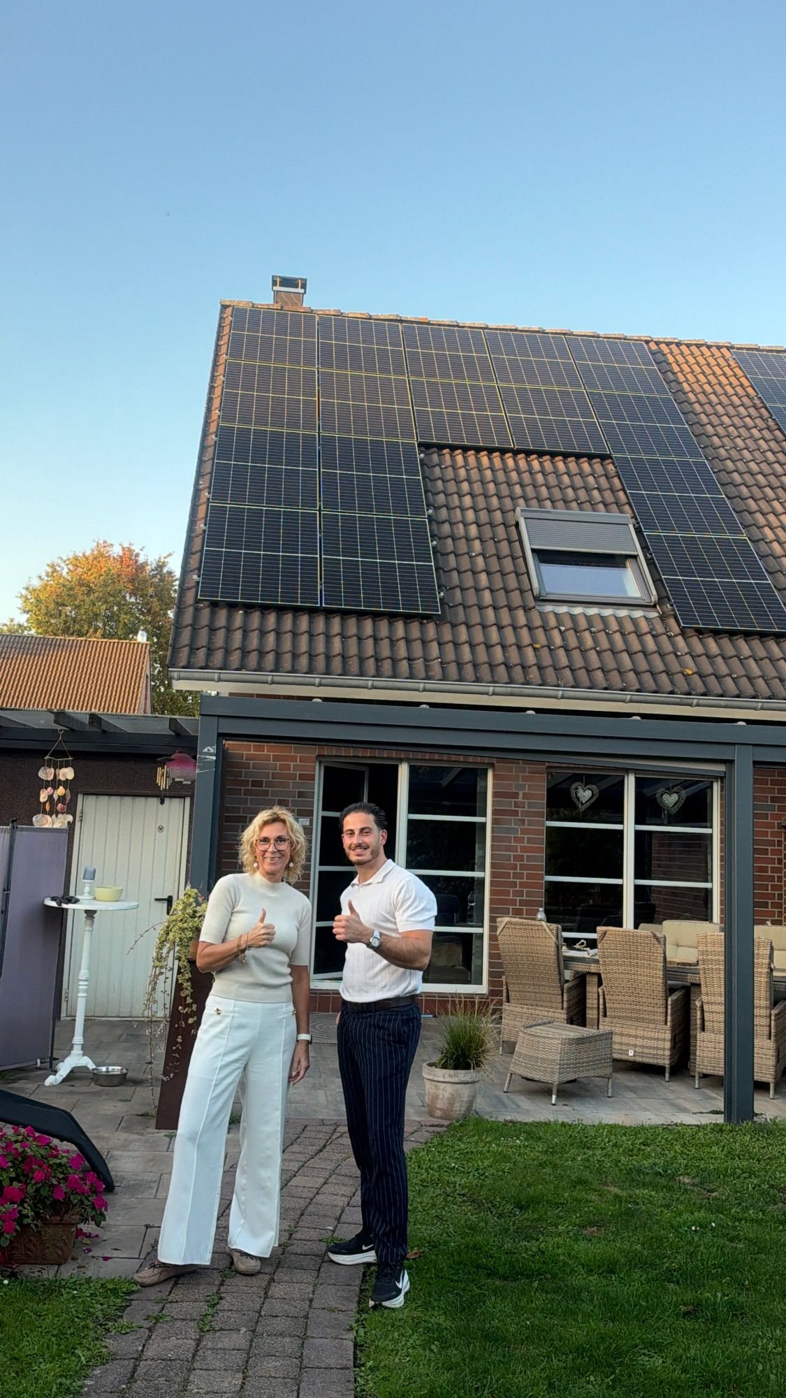 Kundin und Levonova-Berater vor dem Einfamilienhaus mit neuer Photovoltaikanlage, beide mit Daumen hoch